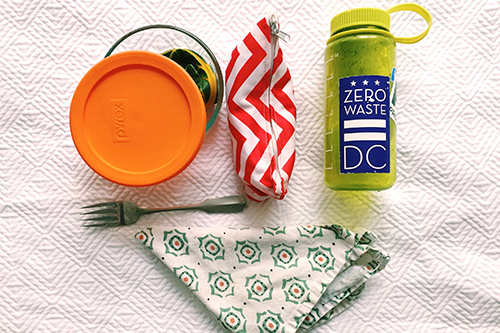Picture of reusable lunch materials. Fork, cloth napkin, reusable water bottle, lunch box. 