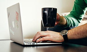 Man with laptop holding coffee mug